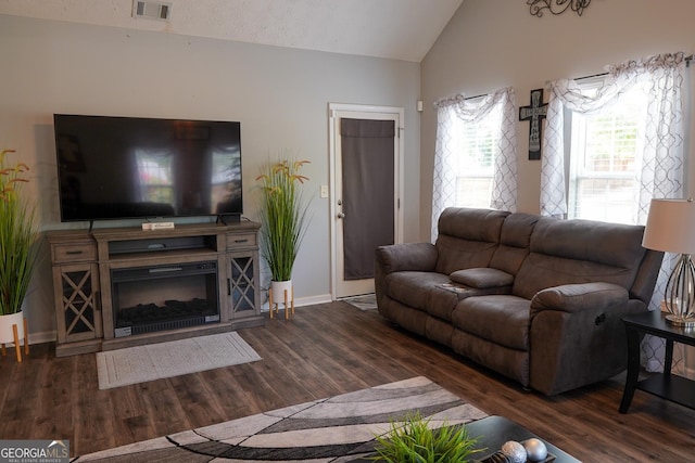 living room with wood finished floors, visible vents, baseboards, vaulted ceiling, and a glass covered fireplace