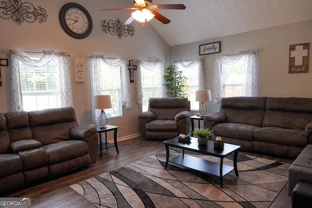 living area with high vaulted ceiling, plenty of natural light, wood finished floors, and a ceiling fan