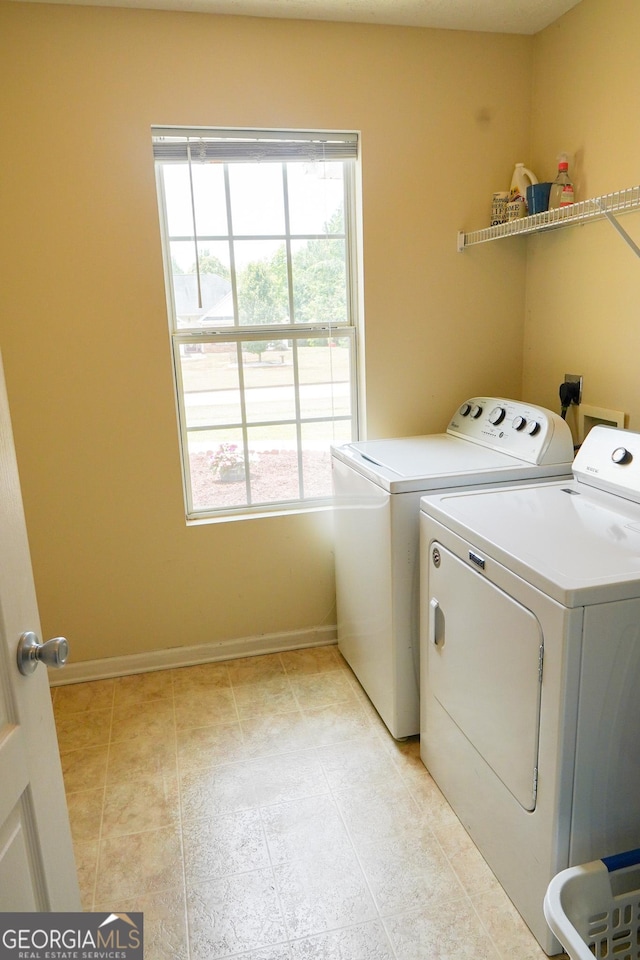 laundry area with laundry area, washing machine and dryer, light tile patterned floors, and baseboards