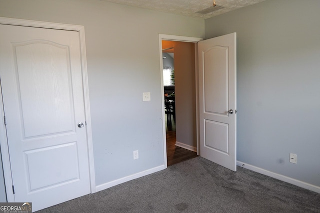 unfurnished bedroom with baseboards and dark carpet