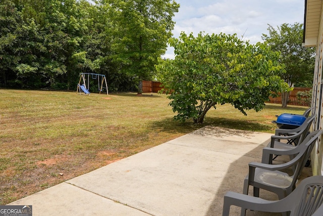 view of yard featuring a patio area, a playground, and fence