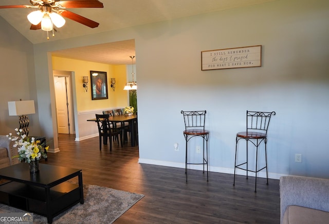 interior space featuring dark wood-style floors, baseboards, vaulted ceiling, and a ceiling fan