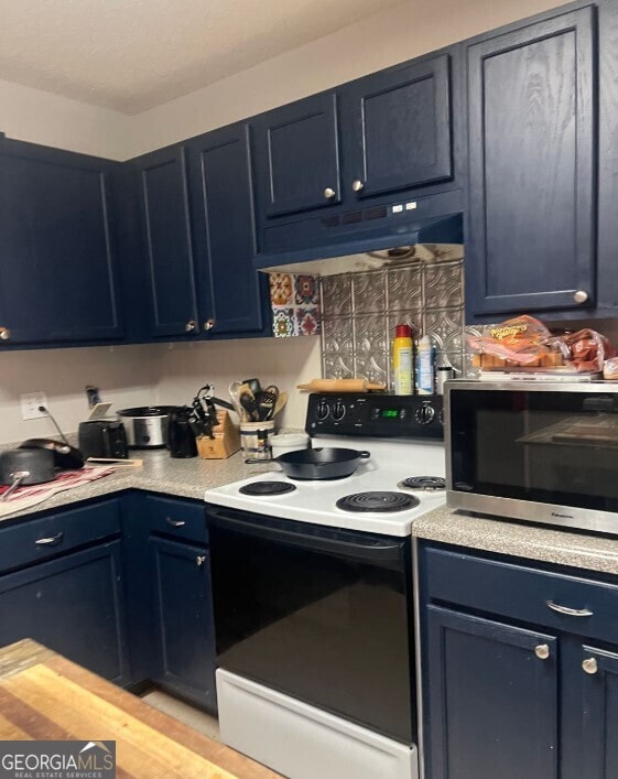 kitchen featuring electric range oven, blue cabinetry, stainless steel microwave, and under cabinet range hood