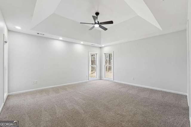 spare room featuring a ceiling fan, a tray ceiling, carpet flooring, and baseboards