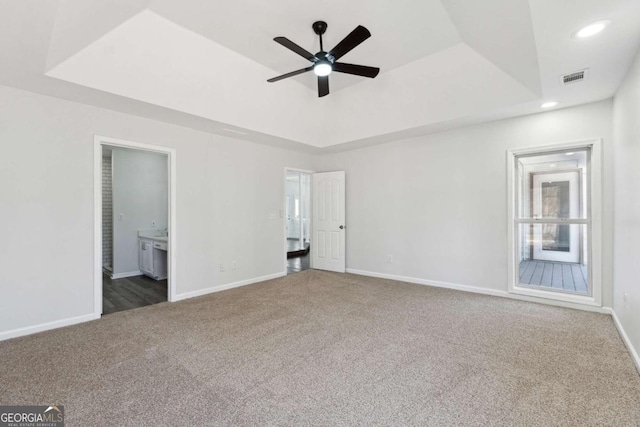 unfurnished bedroom featuring carpet floors, a raised ceiling, and baseboards