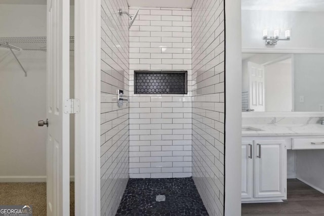 bathroom featuring a spacious closet, tiled shower, and vanity