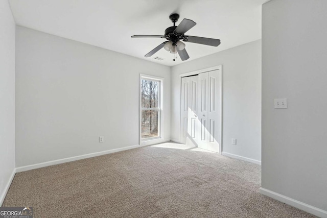 spare room featuring carpet floors, visible vents, ceiling fan, and baseboards