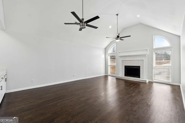 unfurnished living room with a brick fireplace, dark wood finished floors, and baseboards