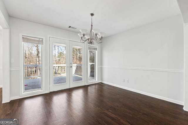 unfurnished dining area featuring baseboards, a notable chandelier, visible vents, and dark wood-type flooring