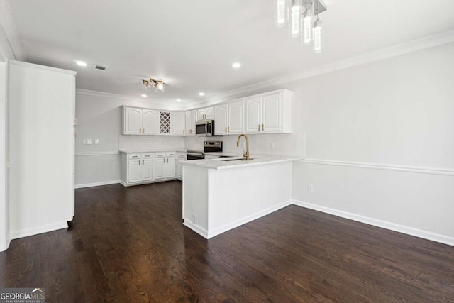 kitchen featuring visible vents, dark wood-type flooring, a peninsula, stainless steel appliances, and crown molding