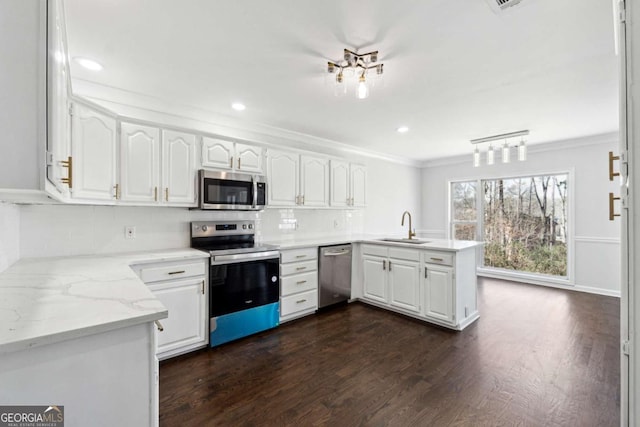 kitchen featuring ornamental molding, a peninsula, appliances with stainless steel finishes, and white cabinetry