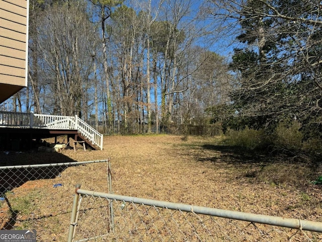 view of yard featuring fence, a deck, and stairs