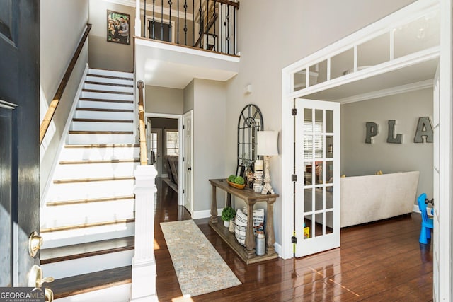 interior space featuring wood-type flooring, a towering ceiling, and baseboards