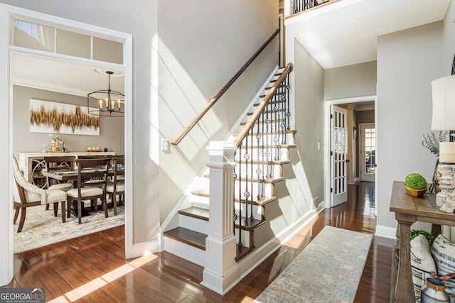 stairway featuring baseboards, wood-type flooring, and a notable chandelier