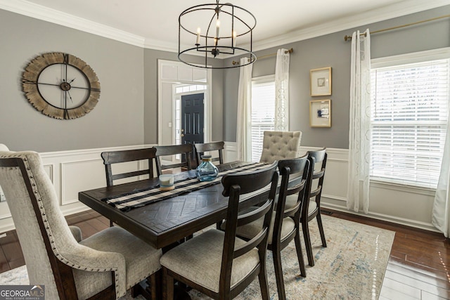 dining room with a wainscoted wall, ornamental molding, wood finished floors, and an inviting chandelier