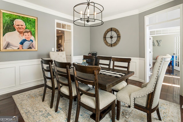 dining area with a wainscoted wall, ornamental molding, wood finished floors, french doors, and a notable chandelier