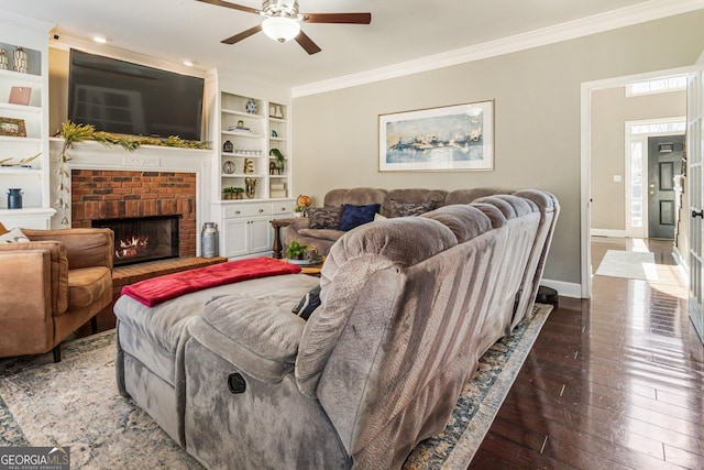 living area featuring built in shelves, a fireplace, baseboards, hardwood / wood-style floors, and crown molding