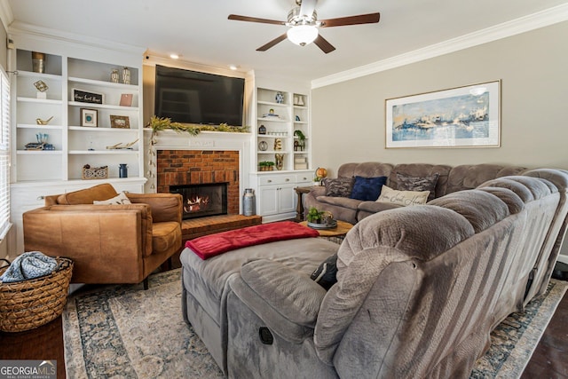 living area featuring built in features, ceiling fan, wood finished floors, crown molding, and a brick fireplace