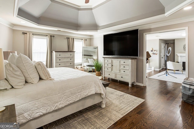 bedroom with baseboards, a raised ceiling, dark wood finished floors, and crown molding