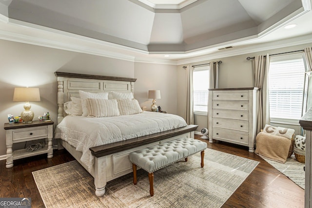 bedroom with ornamental molding, a raised ceiling, visible vents, and wood finished floors