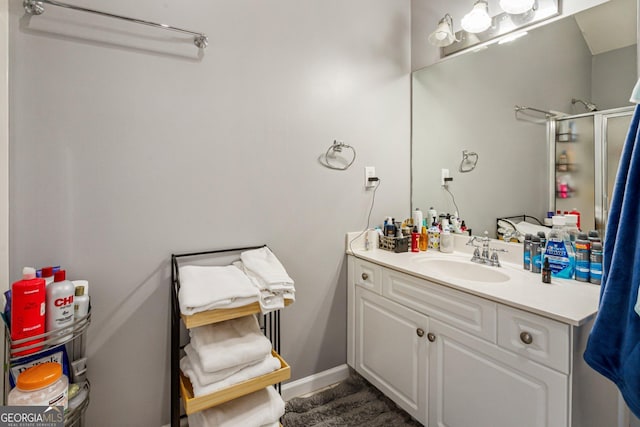 full bath featuring a stall shower, vanity, and baseboards