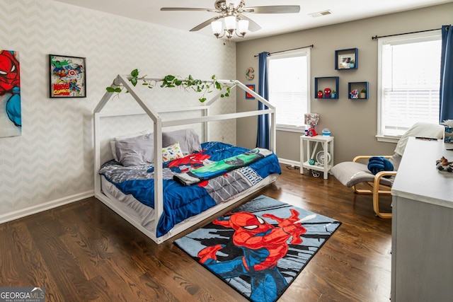 bedroom with wood finished floors, visible vents, baseboards, and wallpapered walls