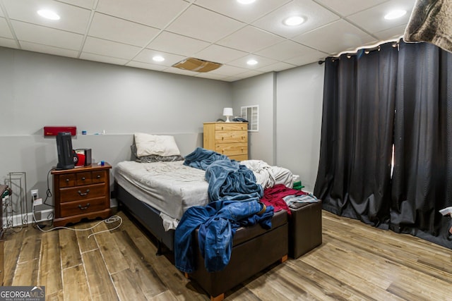 bedroom with a paneled ceiling, wood finished floors, and recessed lighting