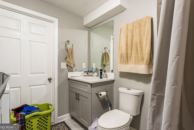 bathroom with baseboards, vanity, and toilet