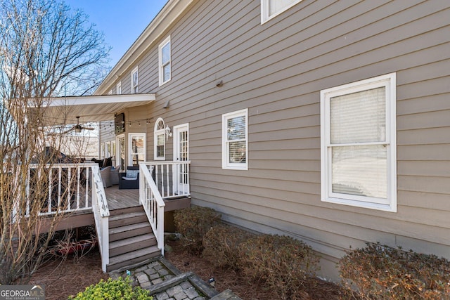 view of exterior entry with a deck and a ceiling fan