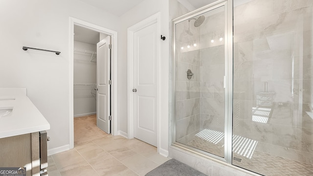 full bathroom featuring a shower stall, a spacious closet, baseboards, and vanity