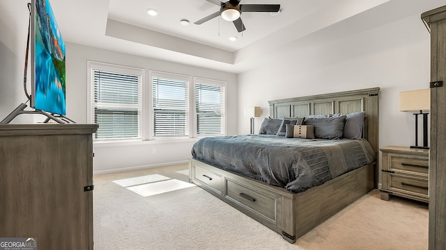 bedroom featuring light carpet, baseboards, a raised ceiling, a ceiling fan, and recessed lighting