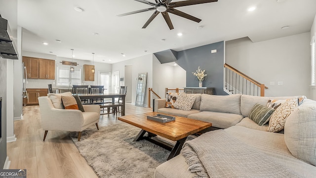 living room featuring stairway, light wood-style flooring, baseboards, and recessed lighting