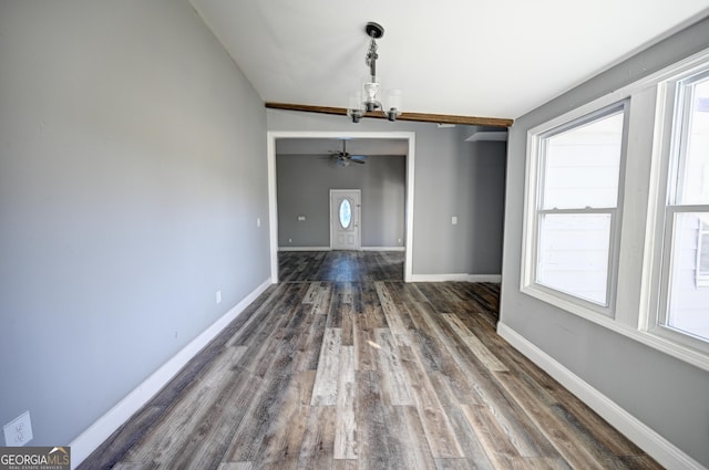 unfurnished dining area featuring ceiling fan with notable chandelier, baseboards, and dark wood-style flooring