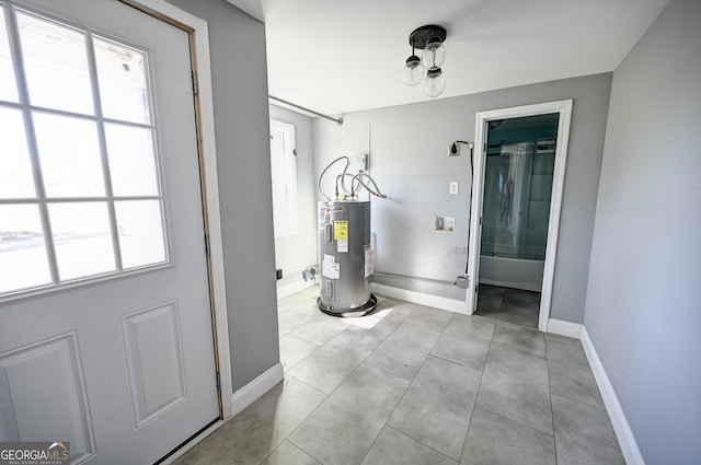 bathroom with tile patterned flooring, combined bath / shower with glass door, baseboards, and electric water heater