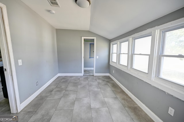 spare room with visible vents, baseboards, and vaulted ceiling