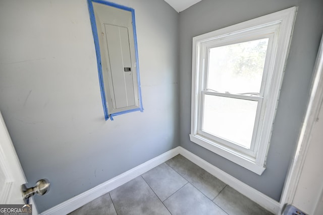 doorway to outside featuring tile patterned floors, baseboards, and electric panel