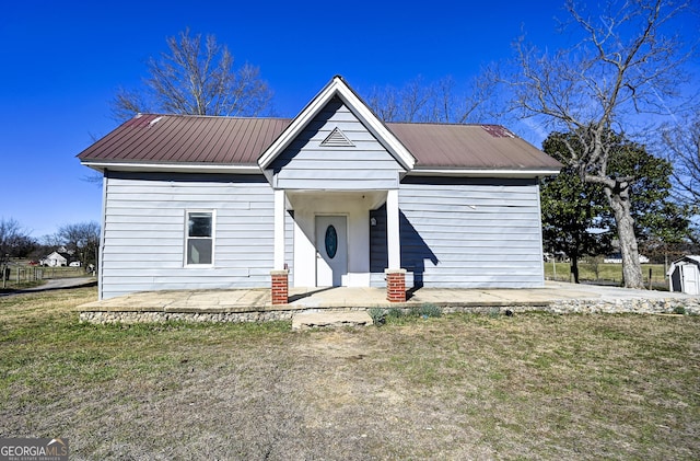 bungalow-style home featuring metal roof, a front lawn, and a patio area