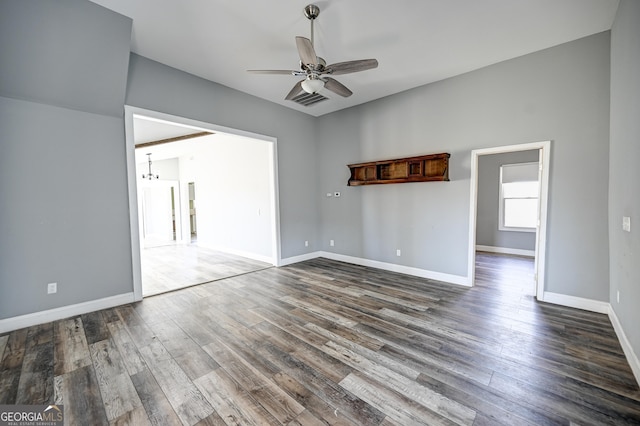 empty room featuring dark wood finished floors, visible vents, baseboards, and a ceiling fan