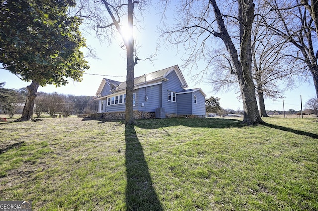 view of side of property with metal roof, central air condition unit, and a lawn