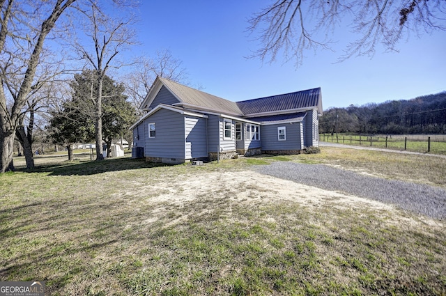 view of side of property with crawl space, a lawn, and metal roof