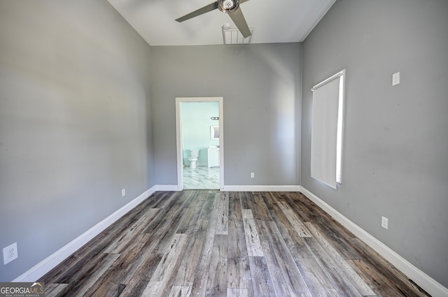 unfurnished room with dark wood-type flooring, a ceiling fan, and baseboards