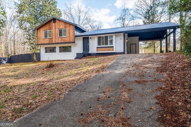 tri-level home featuring metal roof, driveway, an attached carport, and fence