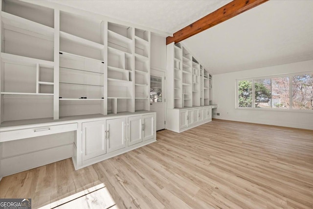 interior space with vaulted ceiling with beams, built in study area, light wood-style flooring, and baseboards