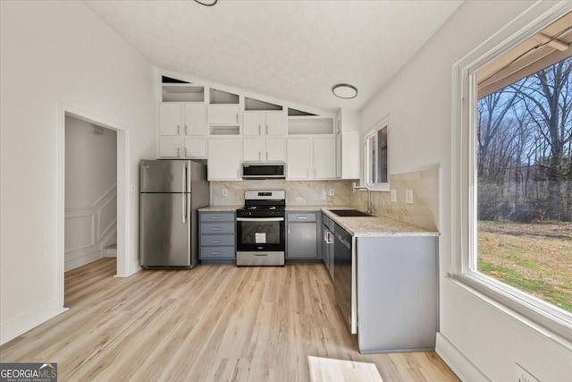 kitchen featuring stainless steel appliances, lofted ceiling, a sink, and plenty of natural light