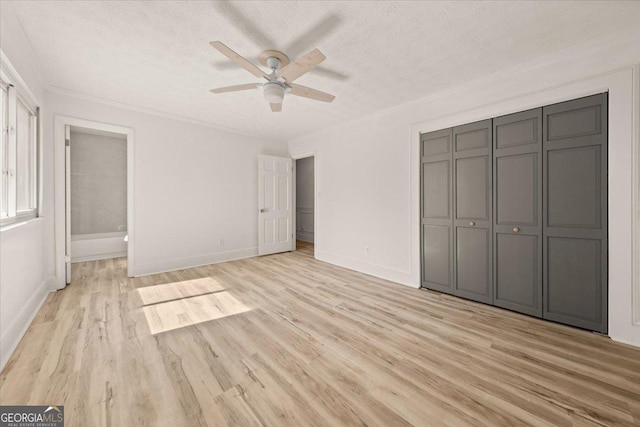 unfurnished bedroom with a textured ceiling, baseboards, and light wood-style floors