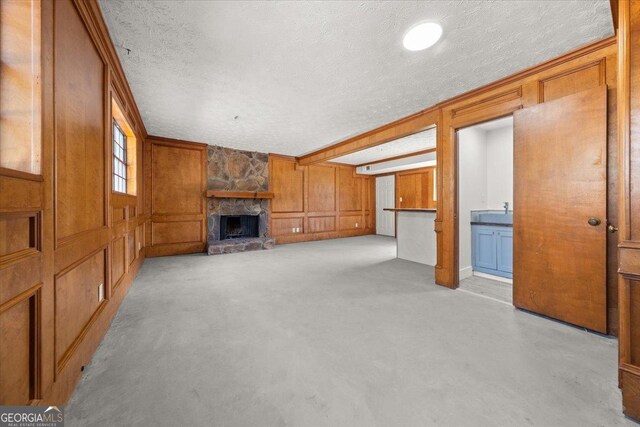 living room featuring wood walls, a textured ceiling, a fireplace with raised hearth, and carpet flooring