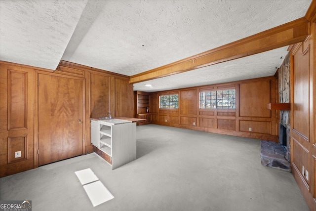 interior space featuring wood walls, a large fireplace, a textured ceiling, and light colored carpet