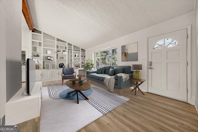 living room with built in shelves, light wood-type flooring, vaulted ceiling with beams, and a textured ceiling