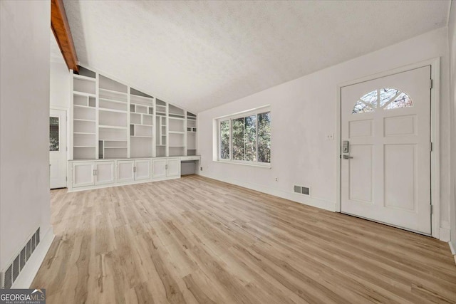 unfurnished living room with lofted ceiling, light wood-style flooring, visible vents, and a textured ceiling