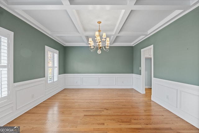 unfurnished dining area with a wainscoted wall, light wood-style floors, beam ceiling, and an inviting chandelier